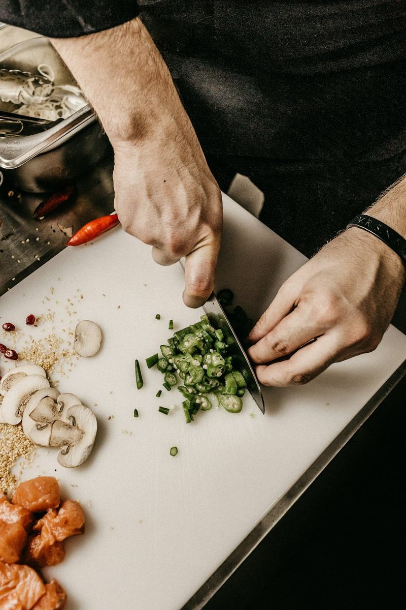 A cook chopping fresh herbs on a board